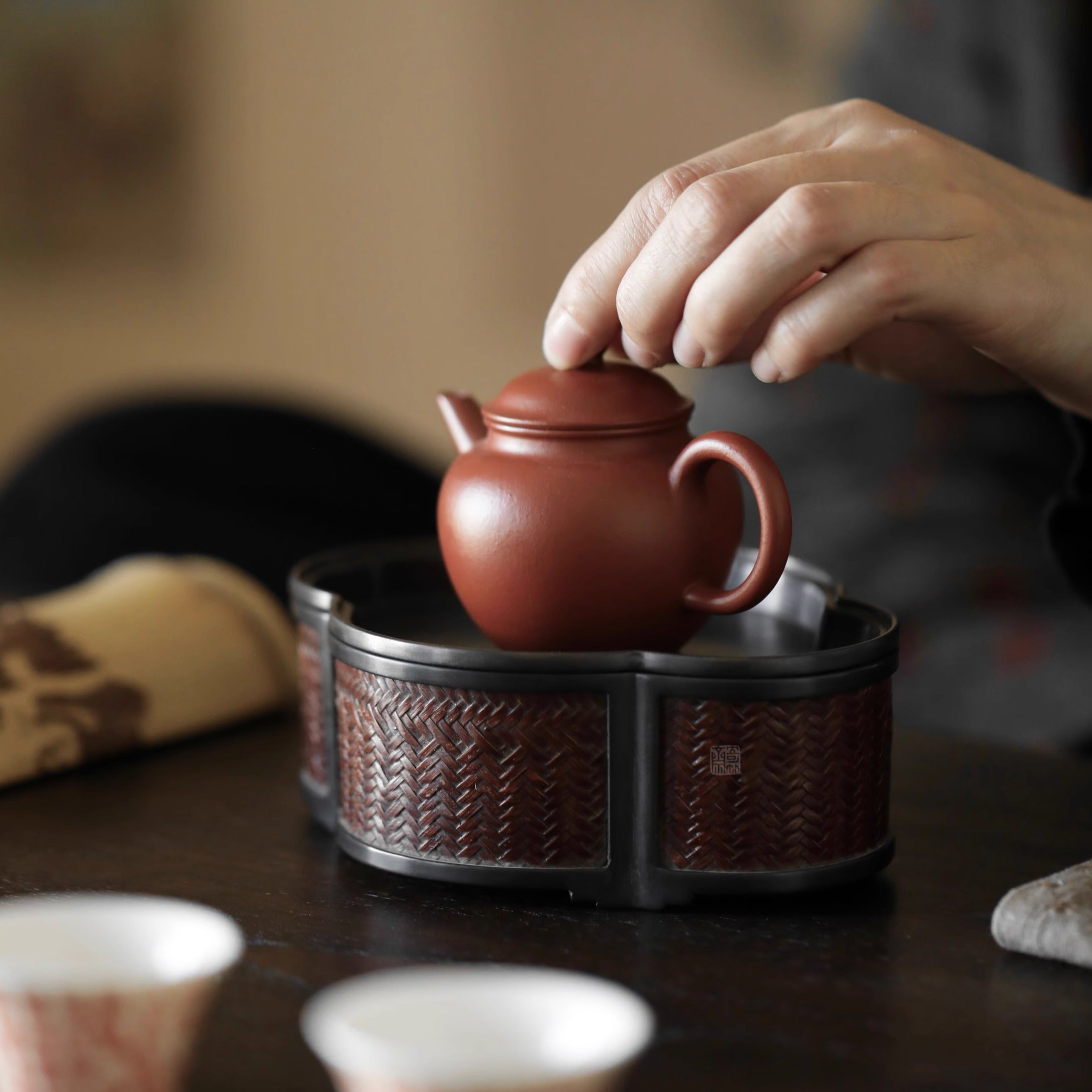 The Takumei Woven Tin Tray by Piexlculpt blends woven rattan warmth with tin craftsmanship. Its handcrafted dual-use design functions as both a tea holder and water tray, offering a refined harmony of practicality