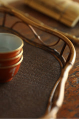The Shirabe Bamboo Tray by Piexlculpt is a handcrafted tea tray combining purple bamboo and rattan weaving in a plum blossom frame design. Its light yet sturdy form embodies balance and grace